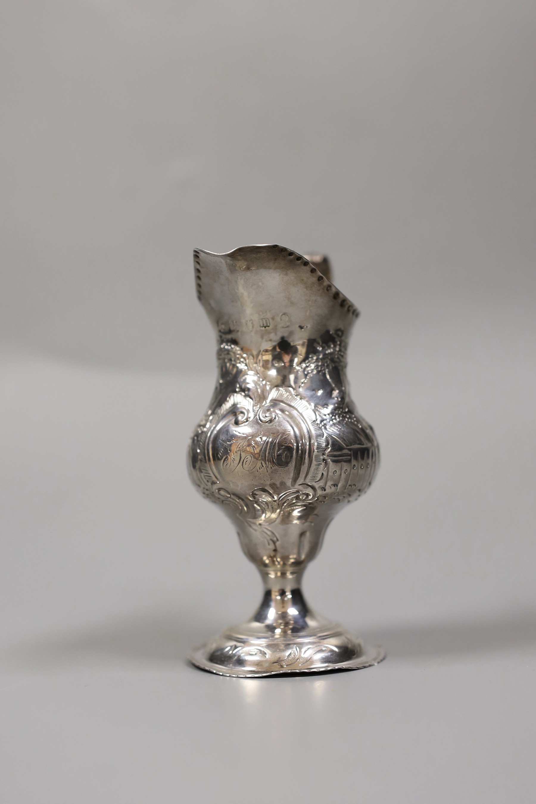 A George III silver inverted pear shaped cream jug, with later embossed decoration, Stephen Adams I, London, 1787, 12.3cm, 73 grams.